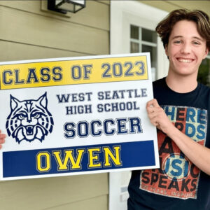 Smiling boy holding a West Seattle High School Soccer yard sign.